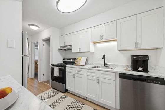 Contemporary kitchen with white cabinets, stainless steel appliances, and marble countertops.