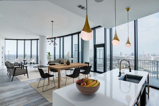 Luxurious open-concept apartment with stunning city views, featuring a modern kitchen island, elegant dining area, and chic living space with floor-to-ceiling windows.