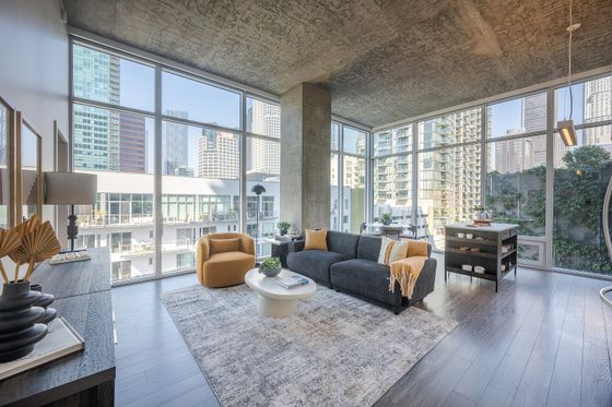 Modern urban living room with floor-to-ceiling windows offering stunning cityscape views, cozy seating, and stylish decor.