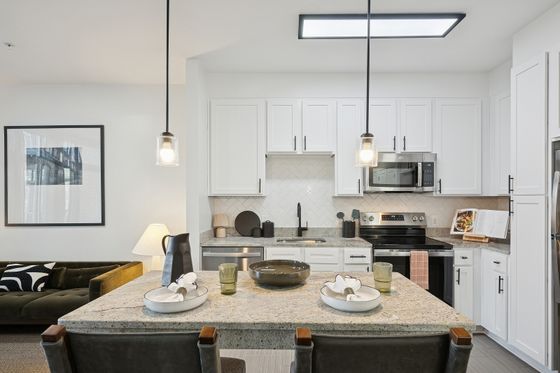 Modern kitchen with elegant lighting, spacious granite countertops, and sleek white cabinetry, perfect for culinary enthusiasts.