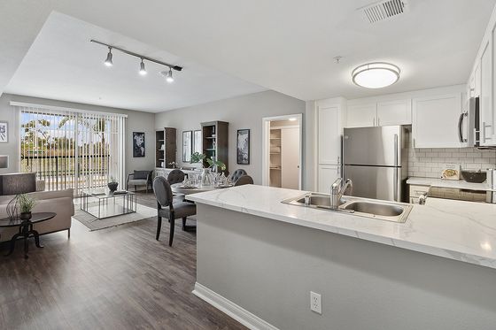 Modern open-concept living space with sleek kitchen, elegant dining area, and inviting living room overlooking a serene patio view.