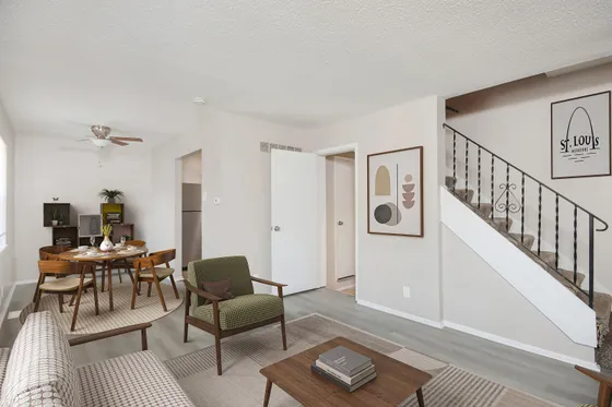 Inviting open-concept living room with stylish furniture, elegant staircase, and cozy dining area.