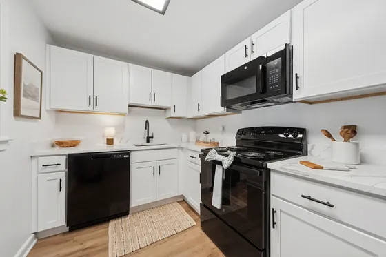 Contemporary kitchen with sleek black appliances, elegant white cabinetry, and stylish marble countertops, perfect for modern living.
