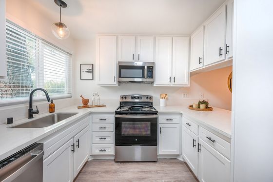 Bright and modern kitchen with sleek white cabinetry, stainless steel appliances, and elegant pendant lighting.