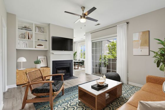 Chic living room with modern furnishings, cozy fireplace, and sleek built-in shelves, leading to a bright dining area through sliding doors to a private balcony.