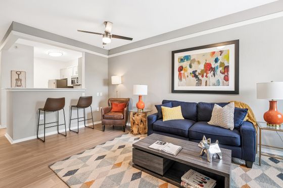 Chic open-concept living room with modern decor, featuring a sleek kitchen bar, cozy seating, and vibrant artwork.