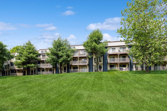 Charming apartment complex surrounded by lush greenery and expansive lawn, offering serene living with nature views.
