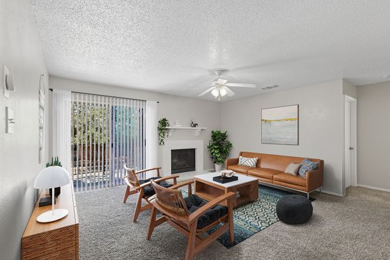 Bright and inviting living room with a cozy fireplace, elegant leather sofa, and floor-to-ceiling windows opening to a lush outdoor view.