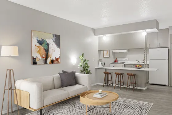 Modern living area with a chic couch, elegant artwork, and open kitchen featuring stylish bar stools, perfect for entertaining.