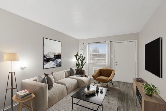 Modern living room with a stylish beige sofa, chic armchair, sleek black coffee table, and elegant decor, bathed in natural light through a large window.