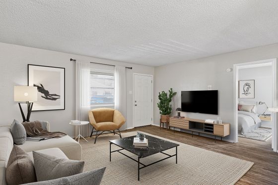 Contemporary living room with plush seating, TV setup, and stylish decor, leading to a cozy bedroom.