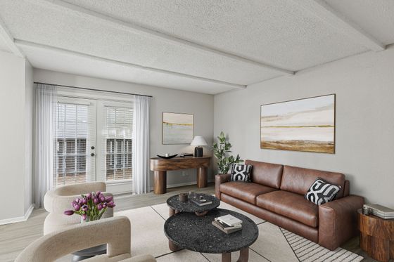 Modern living room with elegant decor, featuring a cozy leather couch, stylish round coffee tables, vibrant tulips, and large windows offering plenty of natural light.