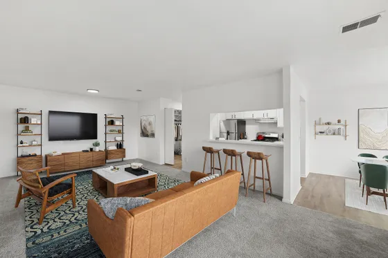 Modern open-plan living area featuring a cozy seating space, stylish bar stools at the breakfast bar, and a glimpse into a chic dining area.