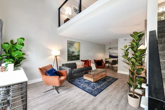 Contemporary open-concept living room with chic furnishings, vibrant accent chairs, and a modern dining area, enhanced by natural light and stylish decor.
