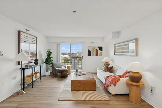 Bright and inviting living room featuring modern decor, elegant wooden flooring, and a cozy seating area with natural light streaming through large windows.