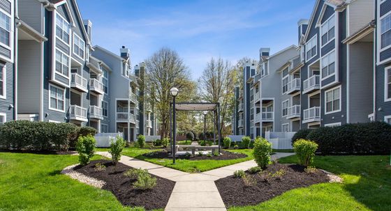 Charming apartment complex featuring modern architecture, lush landscaped gardens, and inviting outdoor seating area.
