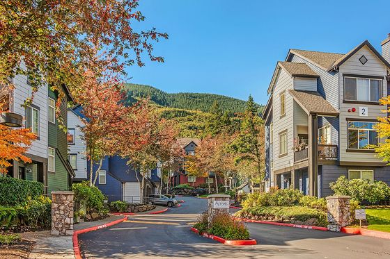 Charming residential neighborhood nestled in vibrant autumn foliage, showcasing modern townhouses with scenic mountain views.