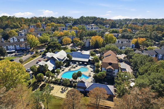 Scenic aerial view showcasing vibrant autumn foliage surrounding a stylish apartment community with a sparkling pool and lush landscaping.