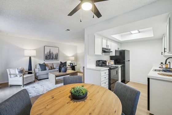 Chic open-plan living space featuring a modern kitchen with black appliances, cozy living room with stylish furniture, and a natural wood dining area.