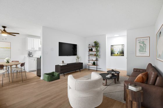 Bright and modern living space featuring a cozy seating area with a leather sofa, sleek wall-mounted TV, and elegant décor. Open dining area with stylish wooden table and chairs, adjacent to a compact kitchen with white cabinetry. Contemporary and inviting atmosphere perfect for relaxation and entertaining.