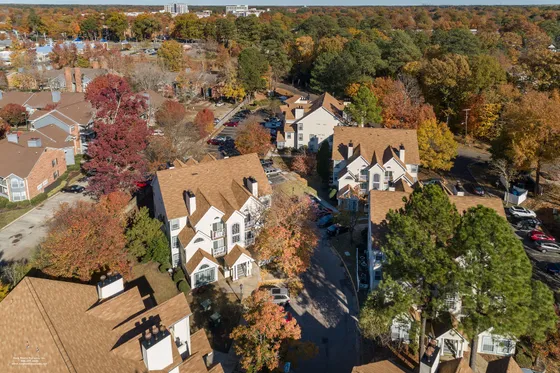Charming aerial view of a picturesque neighborhood with elegant, gable-roofed townhouses nestled among vibrant autumn foliage, showcasing a serene and inviting residential community.