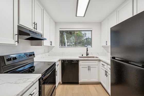 Modern kitchen with sleek black appliances, pristine white cabinets, and elegant marble countertops, offering a blend of style and functionality.