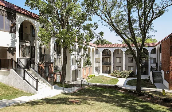 Charming apartment complex with Mediterranean-inspired architecture, featuring stylish archways and vibrant greenery in a serene courtyard setting.