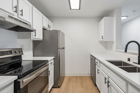 Modern kitchen with stainless steel appliances, sleek white cabinets, and elegant black fixtures.