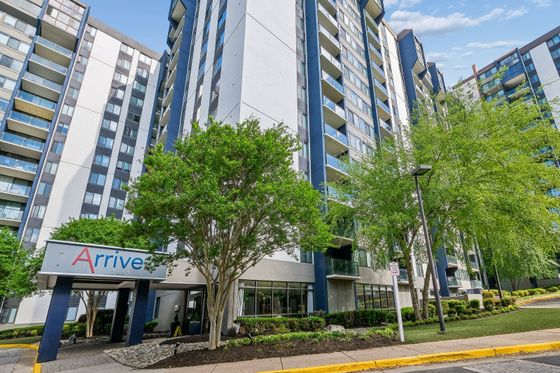 Modern high-rise apartment building with lush green landscaping and elegant entrance at Arrive 2801.