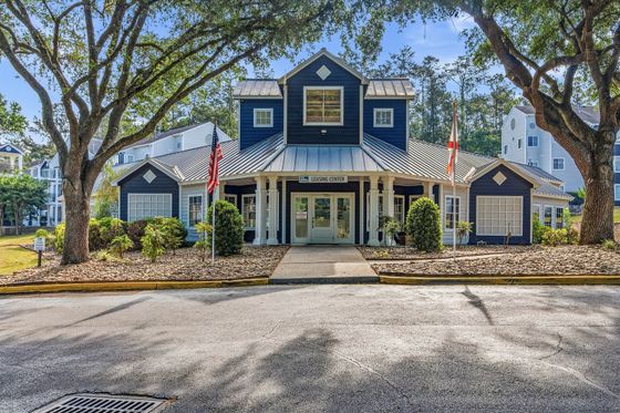 Charming leasing center with a welcoming entrance, surrounded by lush greenery and picturesque trees, perfect for your new home.