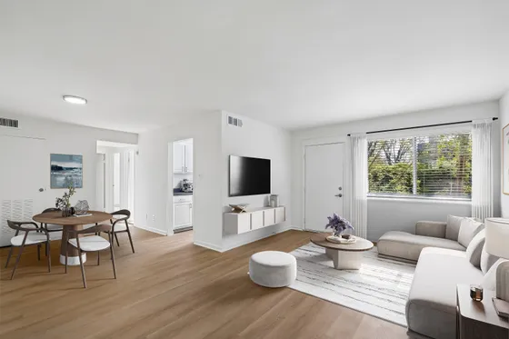 Bright and modern open-plan living area with sleek hardwood floors, a cozy sectional sofa, and a stylish dining set, perfect for a contemporary lifestyle.