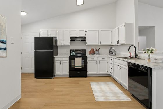Chic modern kitchen with sleek black appliances, white cabinetry, and elegant marble countertops.