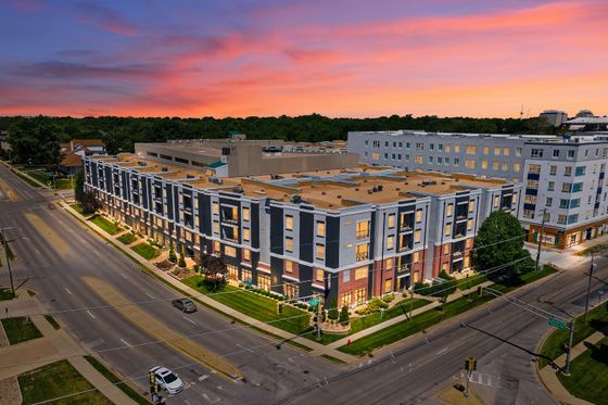 Modern apartment complex illuminated against a breathtaking sunset, showcasing contemporary architecture and vibrant neighborhood scenery.