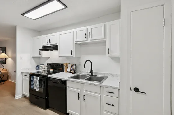 Modern kitchen with sleek black appliances, white cabinetry, and stylish marble countertops for a chic and functional space.