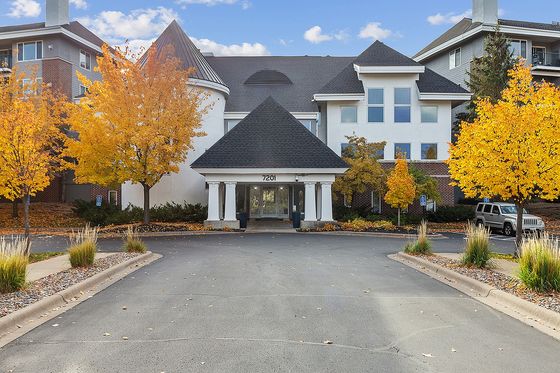 Charming apartment entrance with autumn trees and welcoming facade, perfect for cozy living.