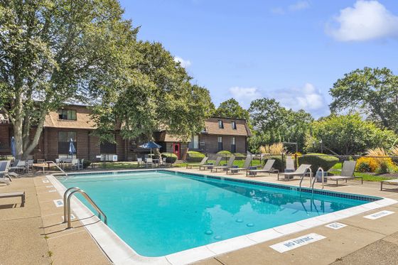 Inviting outdoor pool area surrounded by lush greenery and comfortable lounge chairs, perfect for relaxation and enjoyment.