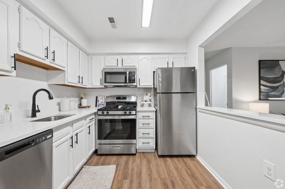 Bright and modern kitchen with white cabinetry, sleek stainless steel appliances, and stylish hardwood flooring.