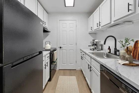 Stylish and modern kitchen with sleek black appliances, white cabinetry, and elegant marble countertops, offering a perfect blend of functionality and style.