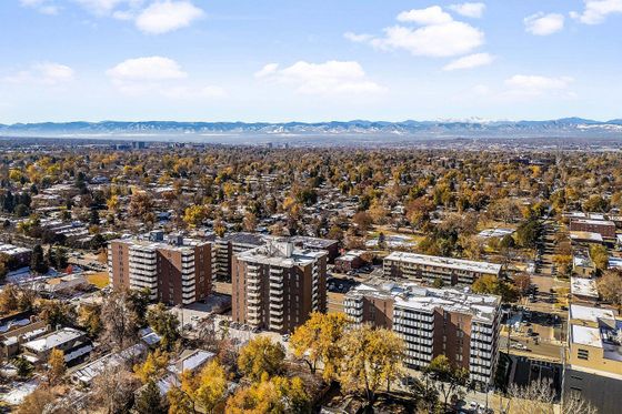 Breathtaking aerial view of a charming residential neighborhood surrounded by lush trees and majestic mountain range in the background, perfect for tranquil apartment living.