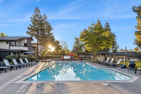 Inviting outdoor pool area with elegant lounge chairs and lush greenery, perfect for relaxation and leisure in a serene setting.
