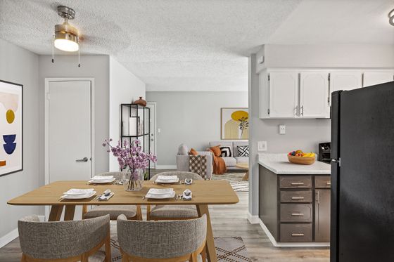 Modern open-concept kitchen and dining area connected to a cozy living room, featuring stylish decor, fresh flowers, and abundant natural light.