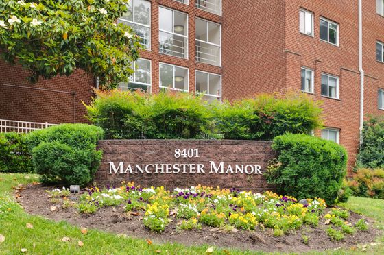 Charming exterior of Manchester Manor, highlighted by vibrant gardens and classic brick architecture.