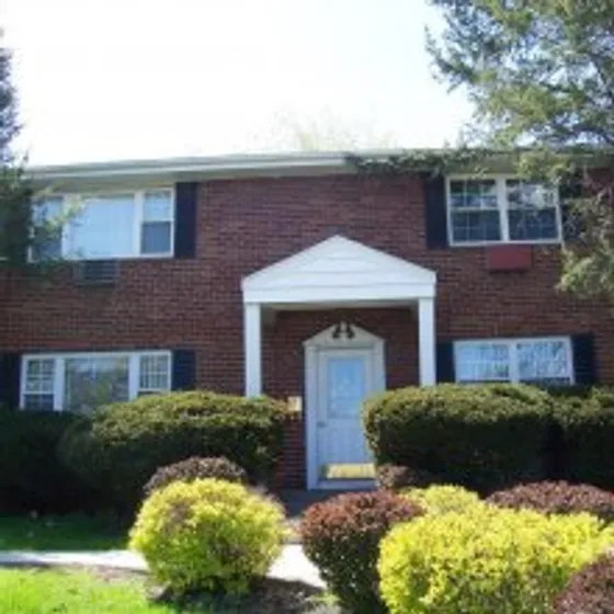 Knox Village Apartments, exterior, red brick building, 2 levels, white covered entrance, grass, trees, bushes
