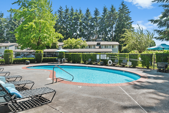 Inviting outdoor pool area surrounded by lush greenery and comfortable lounge chairs, perfect for relaxation and leisure.