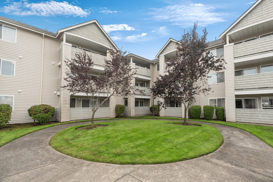 Inviting apartment complex with charming balconies and well-maintained green courtyard under a bright blue sky.