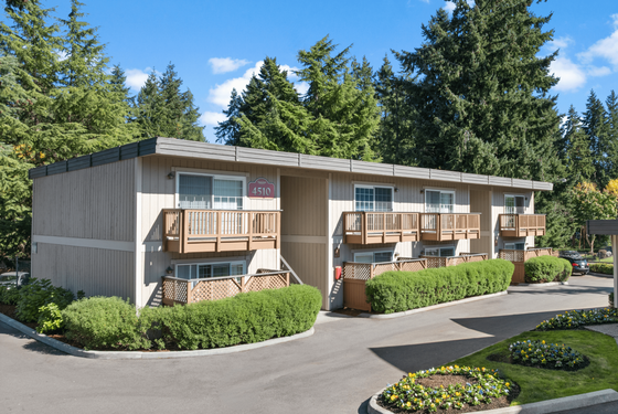 Charming apartment complex with modern balconies surrounded by lush greenery and vibrant landscaping.