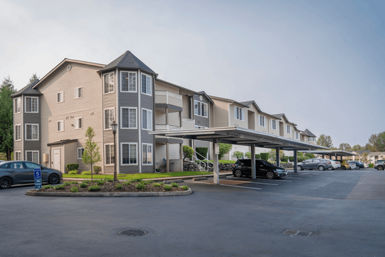 Modern apartment complex showcasing stylish architecture with large windows, well-maintained landscaping, and convenient covered parking.