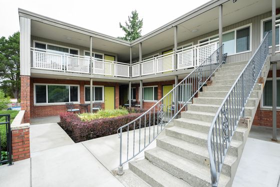 Charming two-story apartment complex with brick facade, spacious balconies, and a welcoming courtyard.