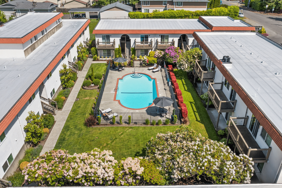 Charming courtyard view with a sparkling central pool, lush greenery, and inviting balconies in a serene apartment complex setting.