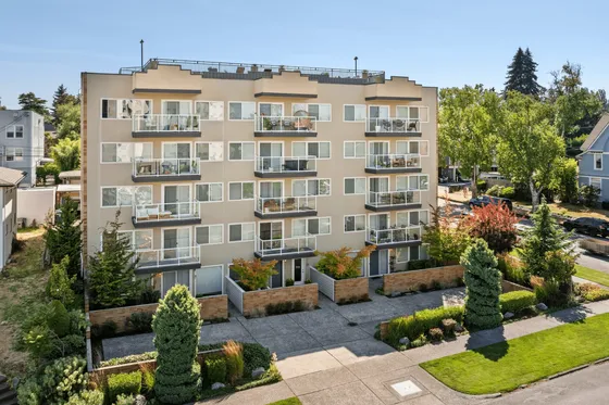 Charming modern apartment building with private balconies, lush greenery, and stylish facade in a serene neighborhood.